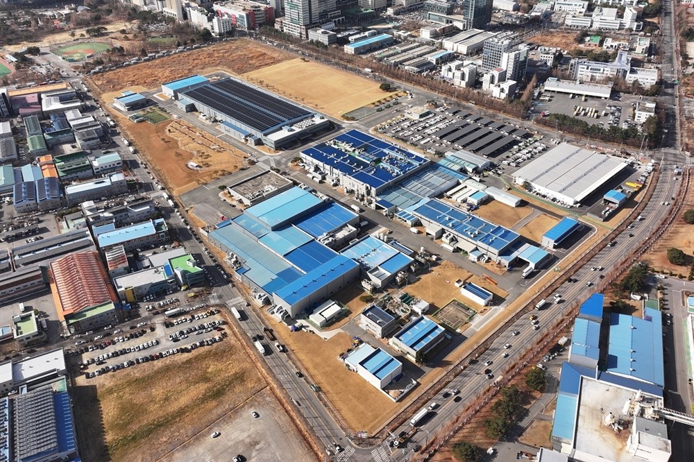 공장 건물과 주차장, 도로가 늘어선 산업단지를 위에서 내려다본 항공 사진. 파란 지붕의 생산동들이 줄지어 있고 오른쪽으로 큰 도로가 지난다.